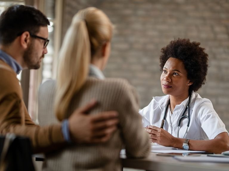 Médica conversando com um casal durante uma consulta.